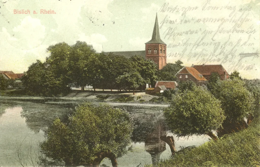Eine ruhige Dorfansicht mit einer Kirche, umgeben von Bäumen und einem Fluss im Vordergrund.