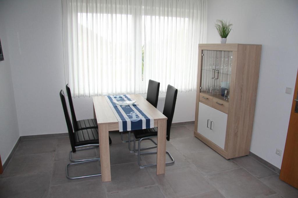 Moderne Essgruppe mit einem Tisch und vier Stühlen in einem hellen Raum, ergänzt durch einen Vitrinenschrank.