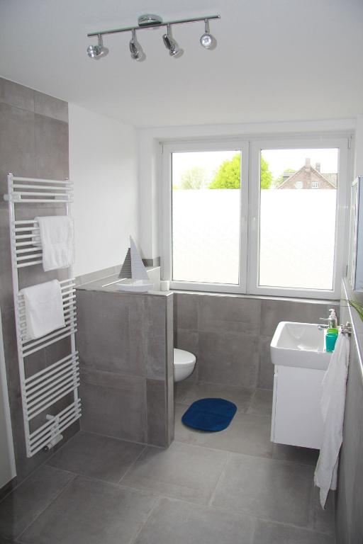 Modernes Badezimmer mit Dusche, Waschbecken, Handtuchhaltern und Fenster mit Blick ins Grüne.