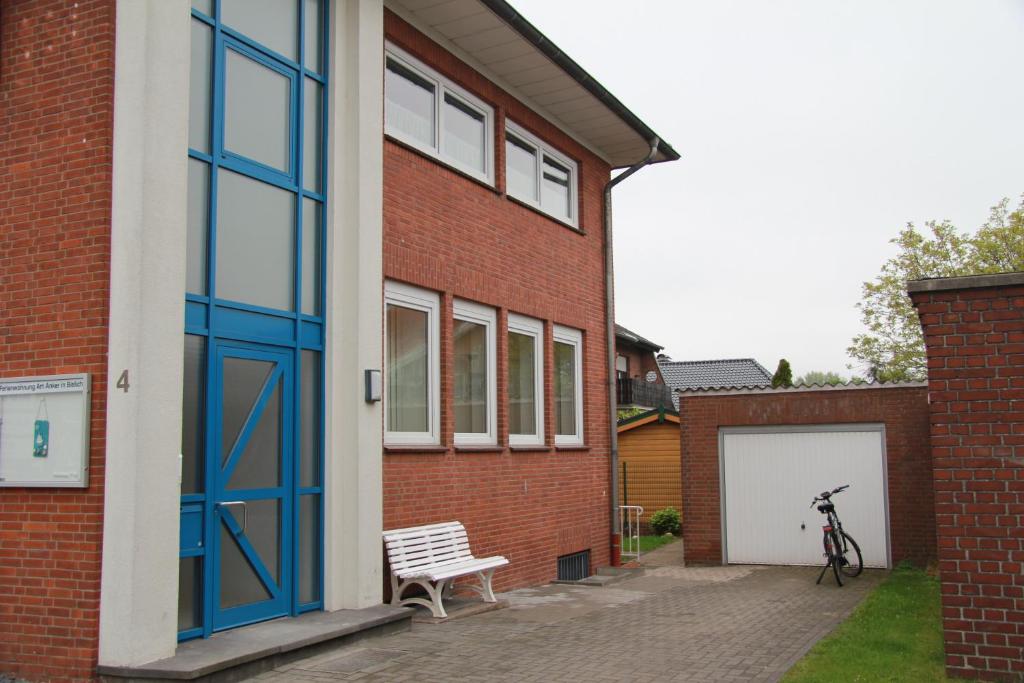 Zwei-geschossiges, rotes Backsteingebäude mit großen Fenstern, einer Bank und einer Garage neben einem Rad.