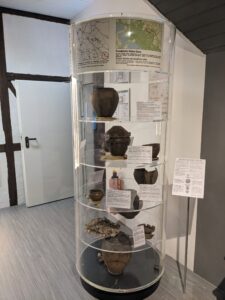 In einem Ausstellungsstück sind verschiedene Tontöpfe und archäologische Artefakte ausgestellt.