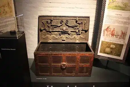 Historische Truhe mit kunstvollem Schloss und Verzierungen in einem Ausstellungsraum.