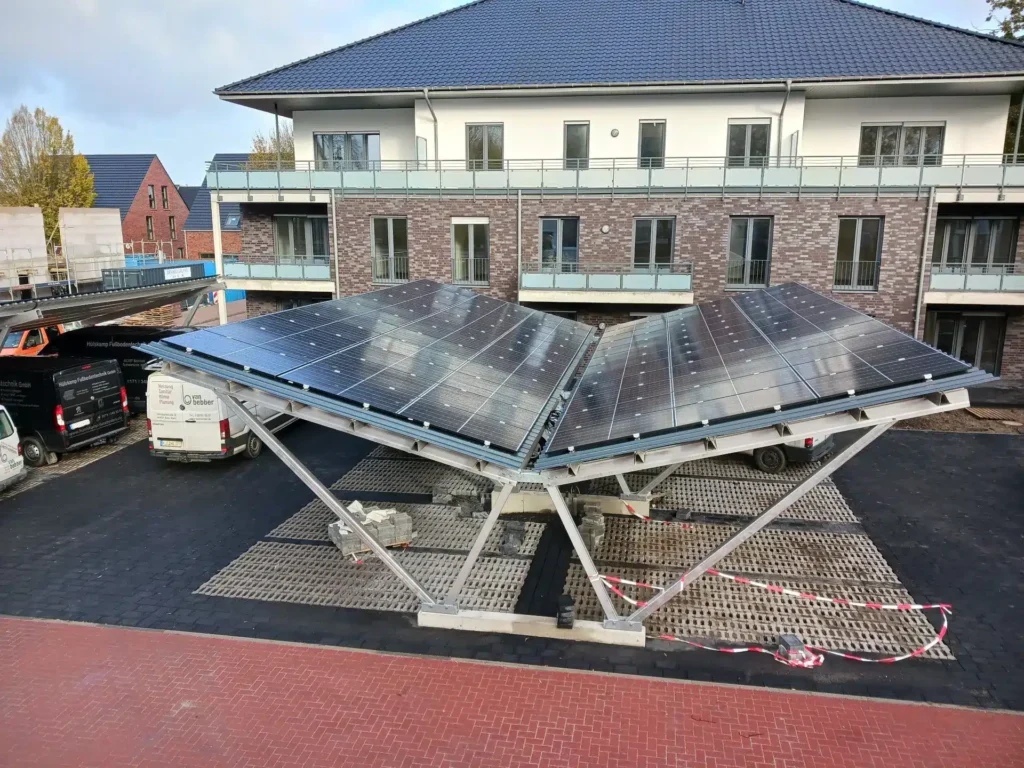 Auf dem Grundstück steht eine Solaranlage mit zwei großen, geneigten Modulen und einem modernen Wohngebäude im Hintergrund.