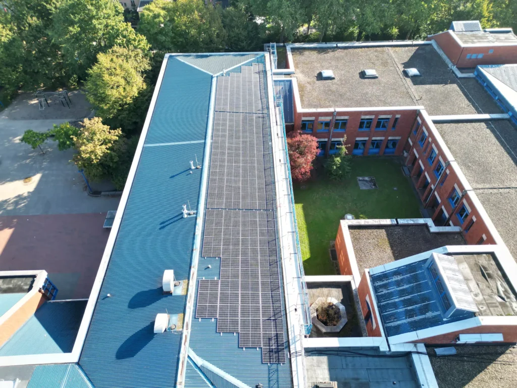 Dachansicht eines Gebäudes mit Solaranlagen und einem grünen Innenhof.