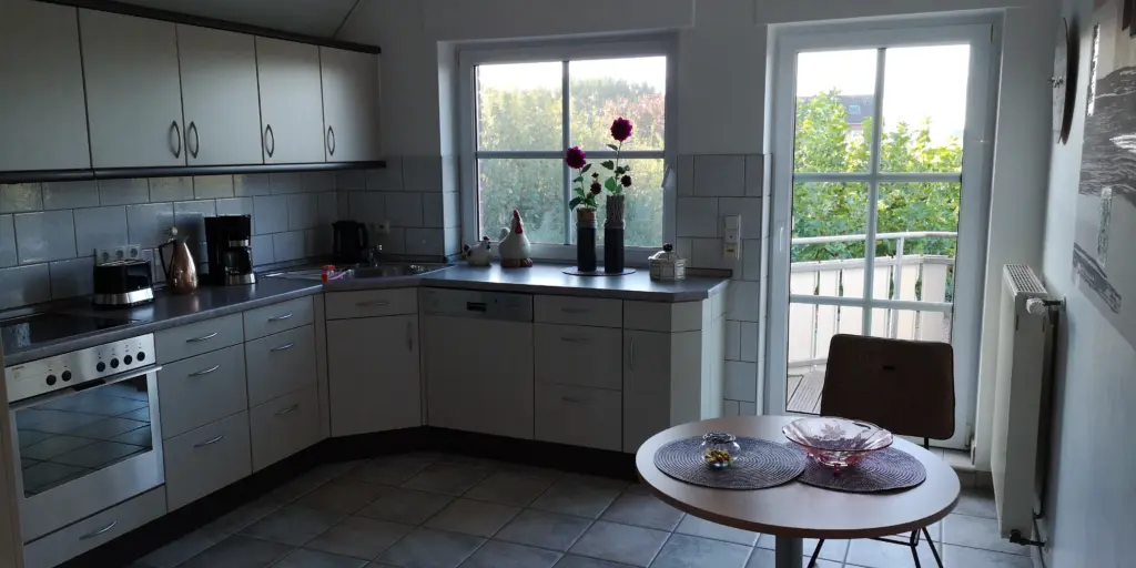 Moderne Küche mit Fenster, Pflanzen auf der Fensterbank und einem kleinen Tisch mit dekorativem Geschirr.