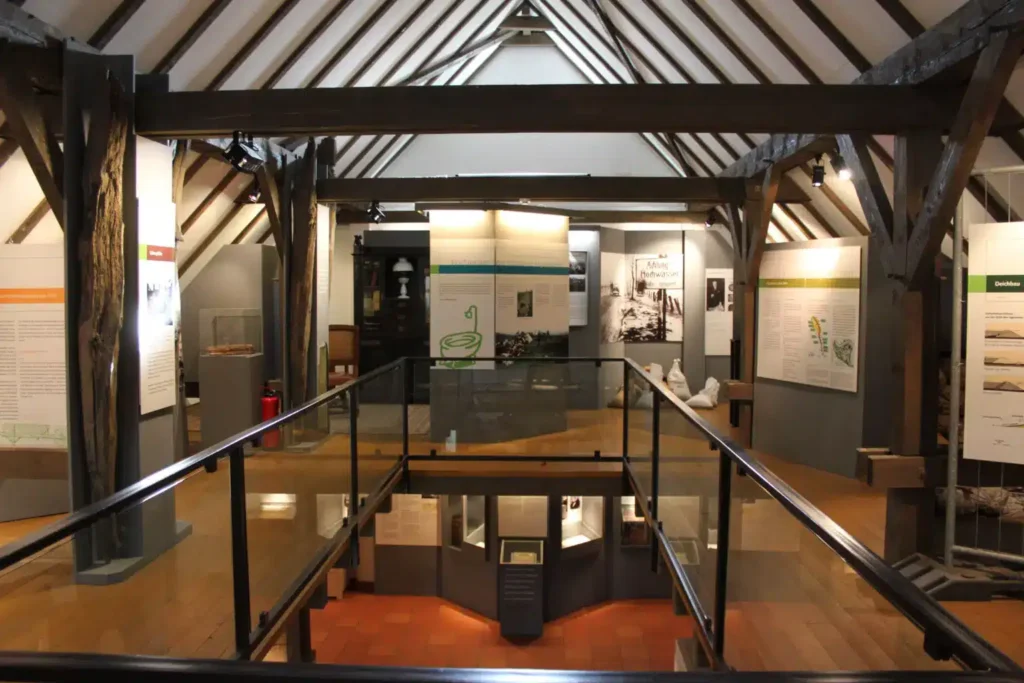 Blick in ein ausgebautes Dorfmuseum mit Holzdecke und verschiedenen Schautafeln auf mehreren Ausstellungsflächen.