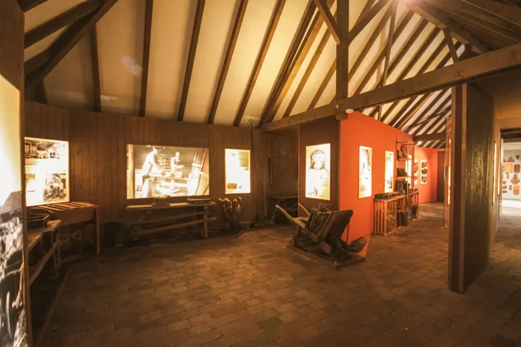 Ausstellungshalle mit historischen Fotografien, Holzstruktur und rustikalen Möbeln im Inneren eines alten Gebäudes.