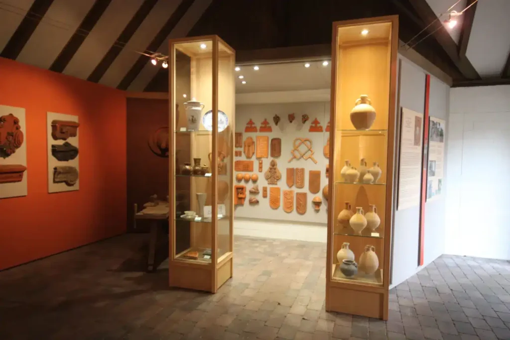 Ein Ausstellungsraum mit Vitrinen, die keramische Objekte zeigen, sowie grafischen Darstellungen an den Wänden.