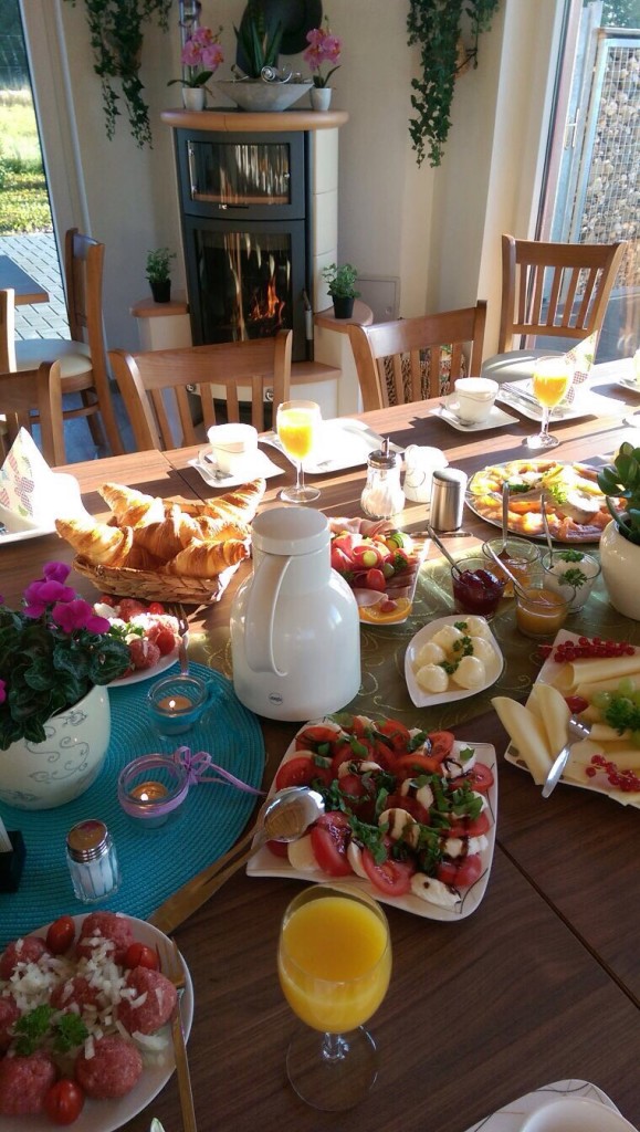 Ein reichhaltiges Frühstücksbuffet mit frischem Obst, Kräutersalat, Croissants, Säfte und einer ansprechenden Dekoration.