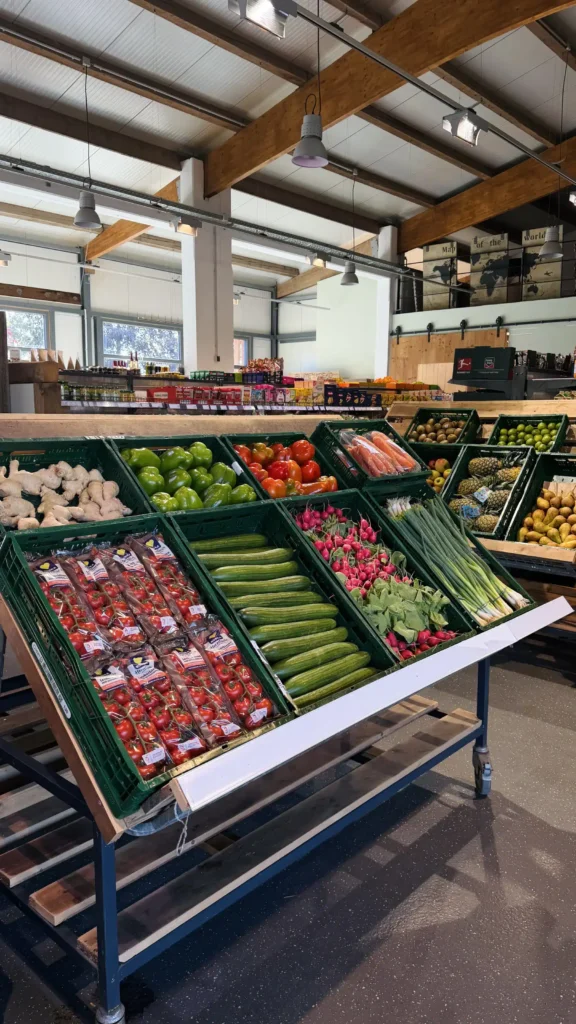 Ein Frischmarkt mit verschiedenen Obst- und Gemüsesorten, übersichtlich in Regalen angeordnet.