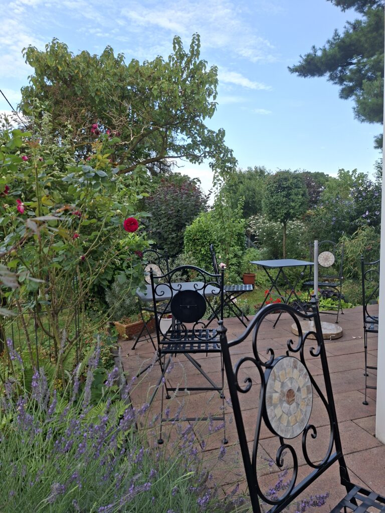 Gemütlicher Gartenbereich mit Gartenmöbeln, Lavendel und grünen Pflanzen unter einem klaren Himmel.